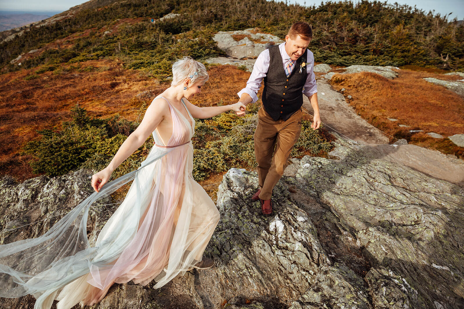  Couple holds hands and hikes along summit of Mt. Mansfield near Stowe, Vermont after their elopement 