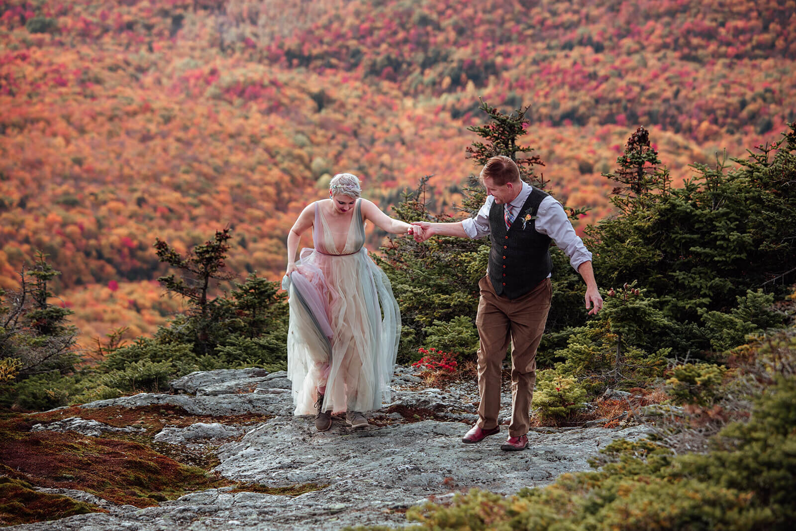  Brides dress flows in the wind as she and the groom enjoy a moment on summit of Mt. Mansfield near Stowe, Vermont after their elopement 