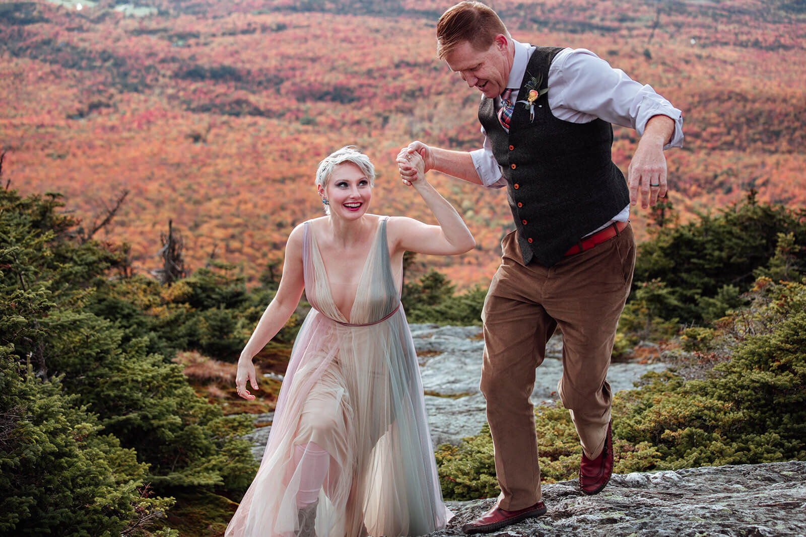  Brides dress flows in the wind as she and the groom enjoy a moment on summit of Mt. Mansfield near Stowe, Vermont after their elopement 