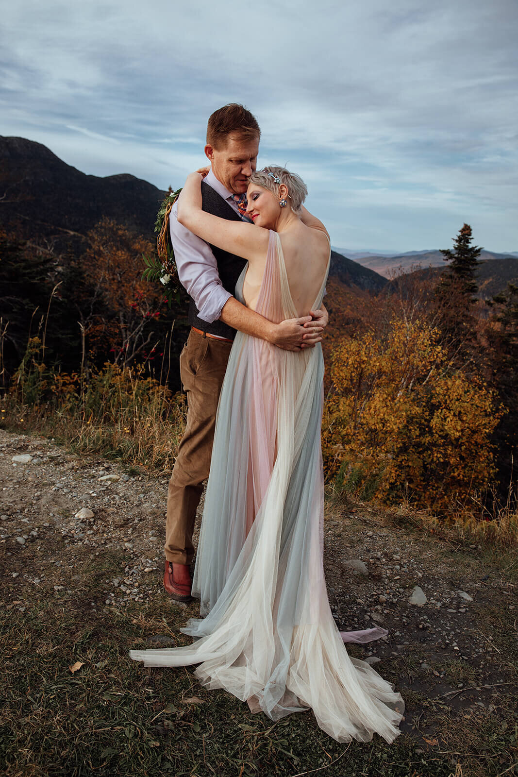  Bride in her rainbow dress and Groom hug during their Vermont elopement on Mt. Mansfield near Stowe 