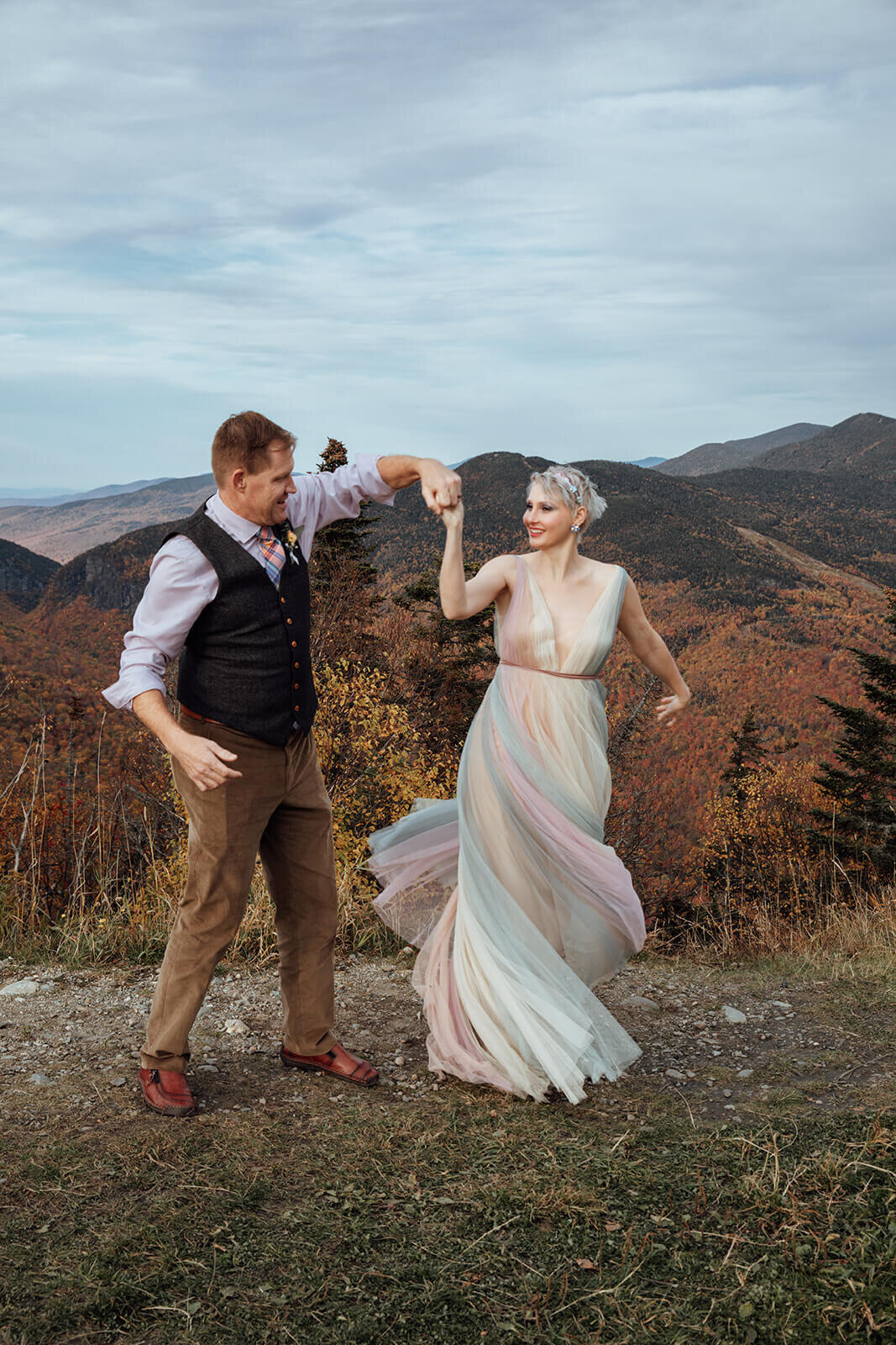  Bride in her rainbow dress and Groom dance and spin during their Vermont elopement on Mt. Mansfield near Stowe 