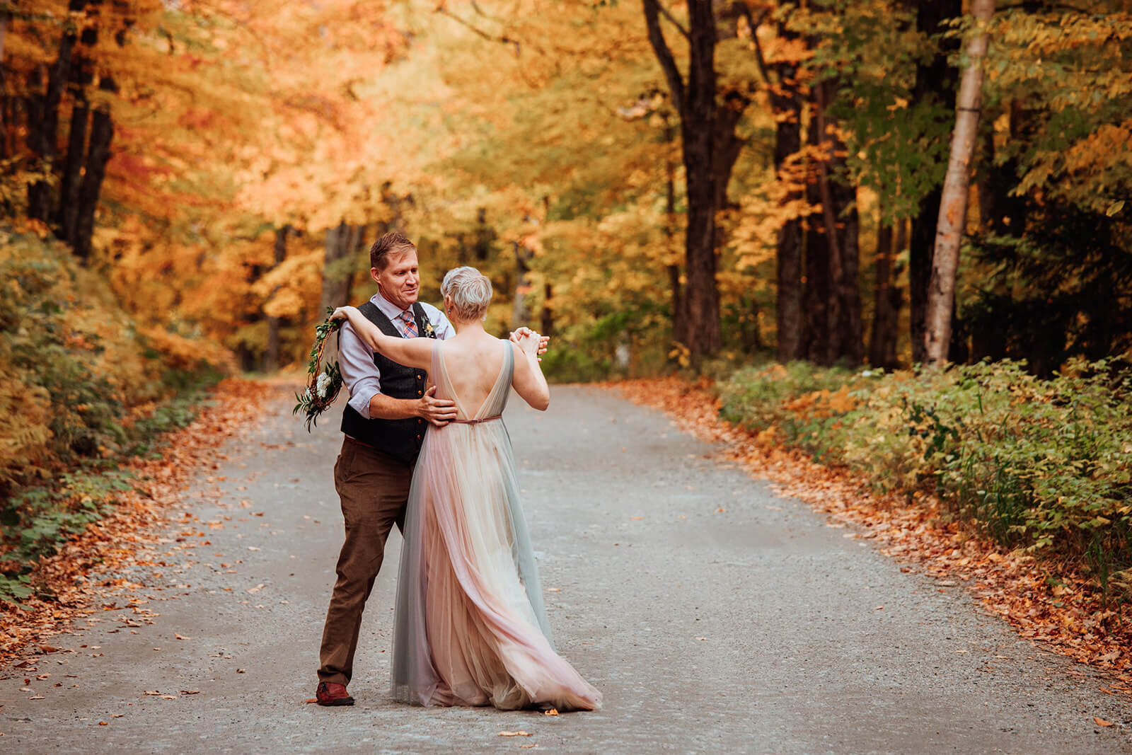  Couple dances through colorful tree tunnel after their elopement in Stowe, Vermont on Mt. Mansfield 