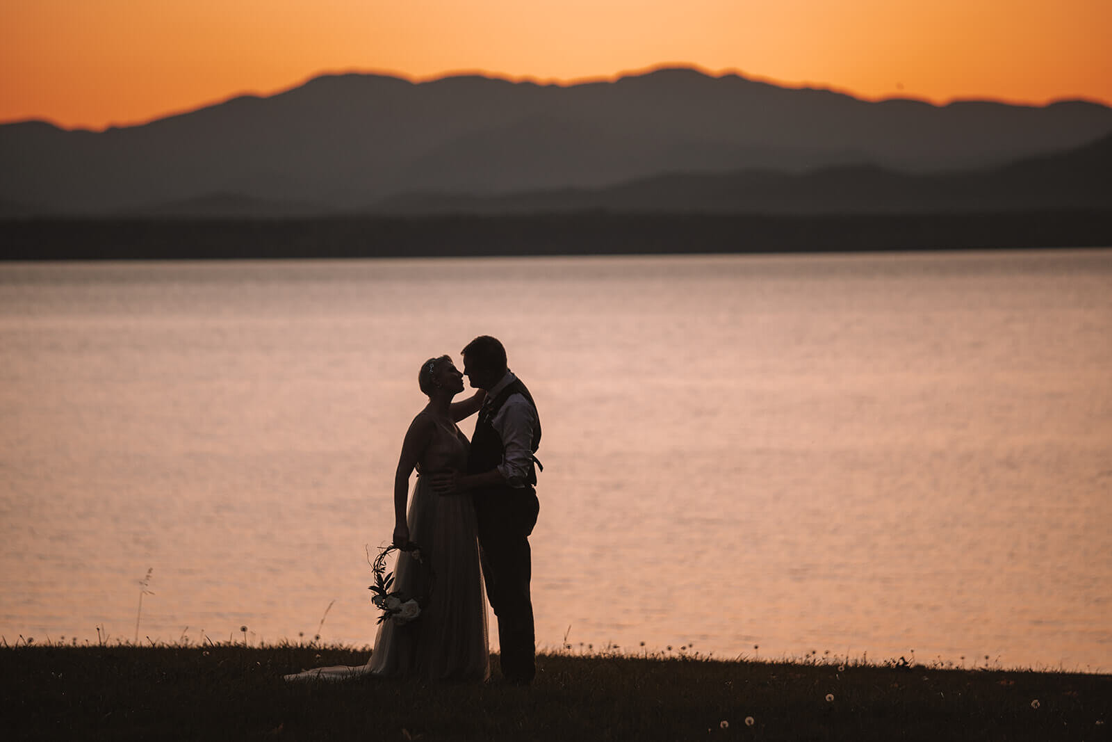  Bride and groom kiss at sunset in front of Lake Champlain outside Burlington, Vermont after their elopement 