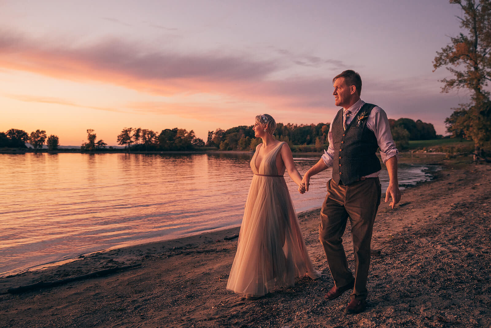  Bride and groom walk along Lake Champlain near Burlington, VT after their fall elopement 
