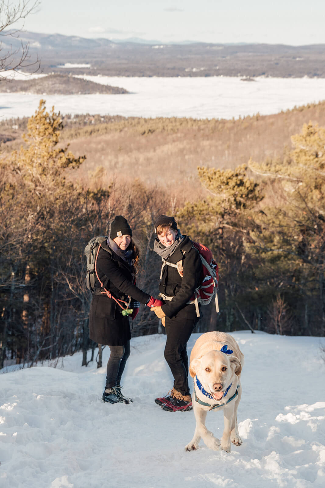  Couple cold on the summit of Mt. Major in New Hampshire in the winter with their dog. New Hampshire couples photographer 