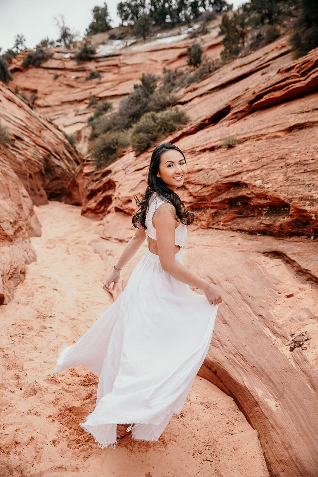  Bride runs down canyon during secluded elopement in a technical canyon outside of Zion National Park in southern Utah  