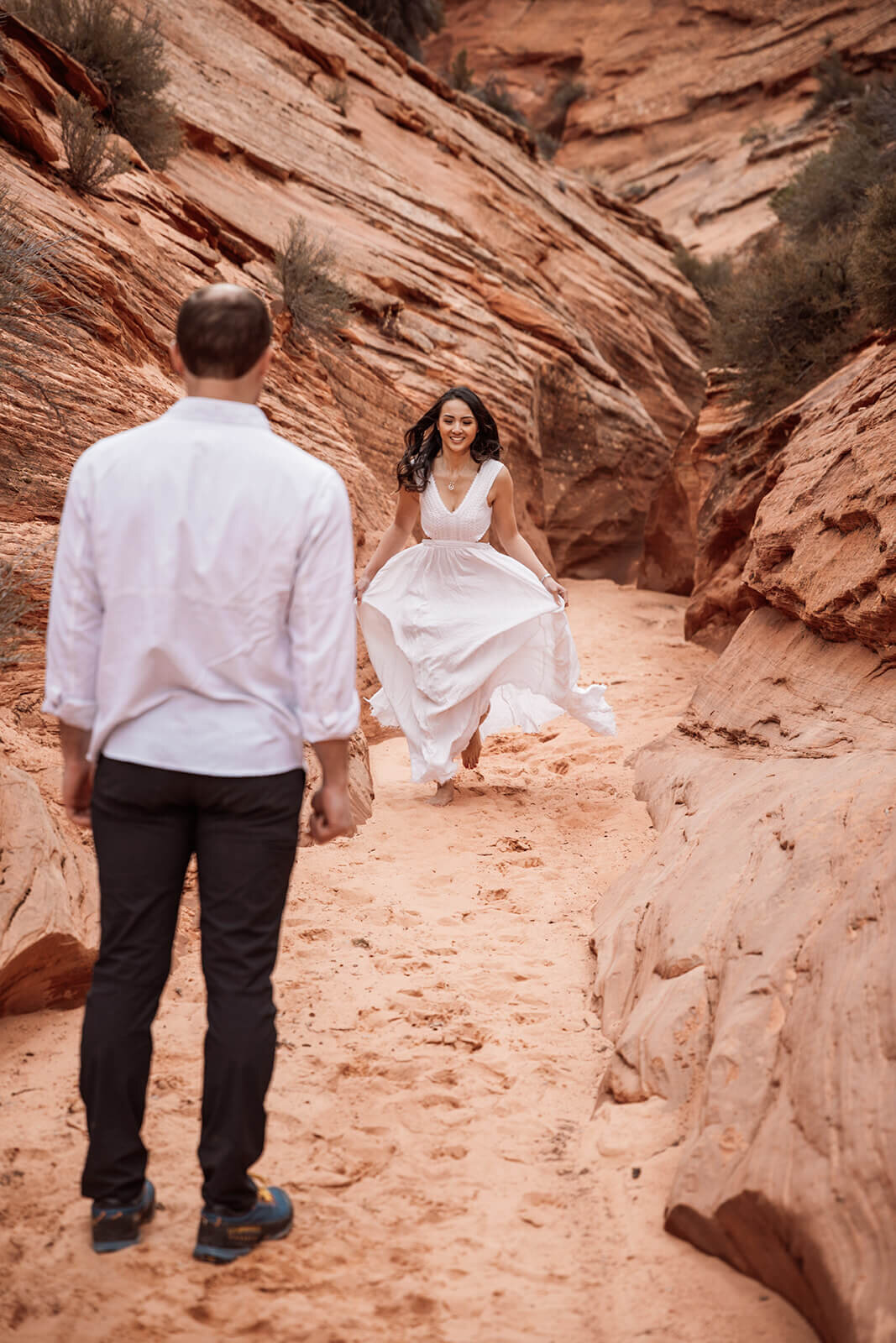  Bride runs down canyon during secluded elopement in a technical canyon outside of Zion National Park in southern Utah. Utah elopement photographer 