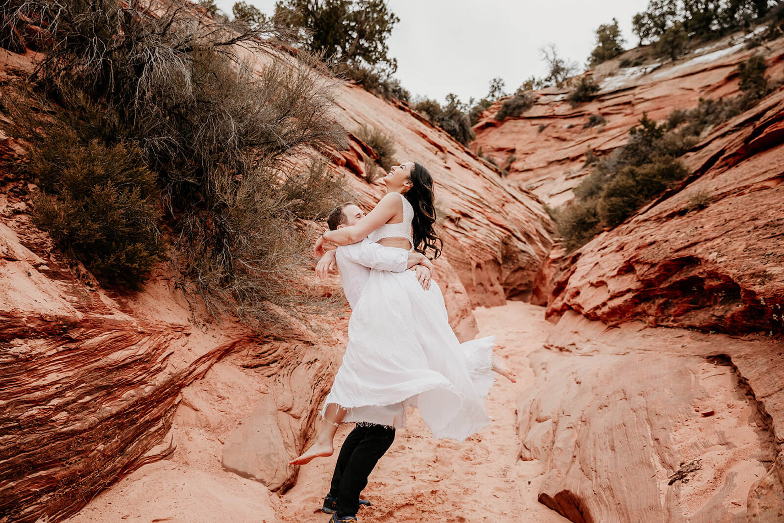  Bride runs down canyon during secluded elopement in a technical canyon outside of Zion National Park in southern Utah. Zion elopement photographer 