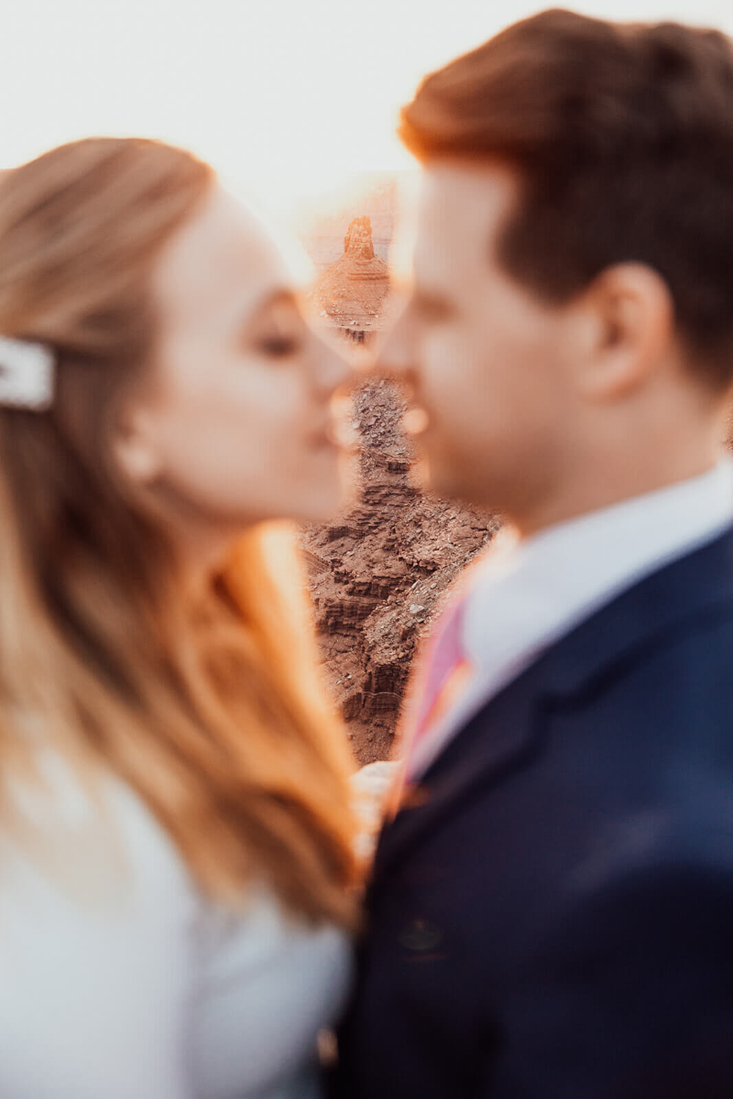  Couple kiss during anniversary celebration at sunset at Dead Horse Point State Park and the La Sal Mountains near Moab, Utah with incredible views and hiking. Utah wedding photographer 