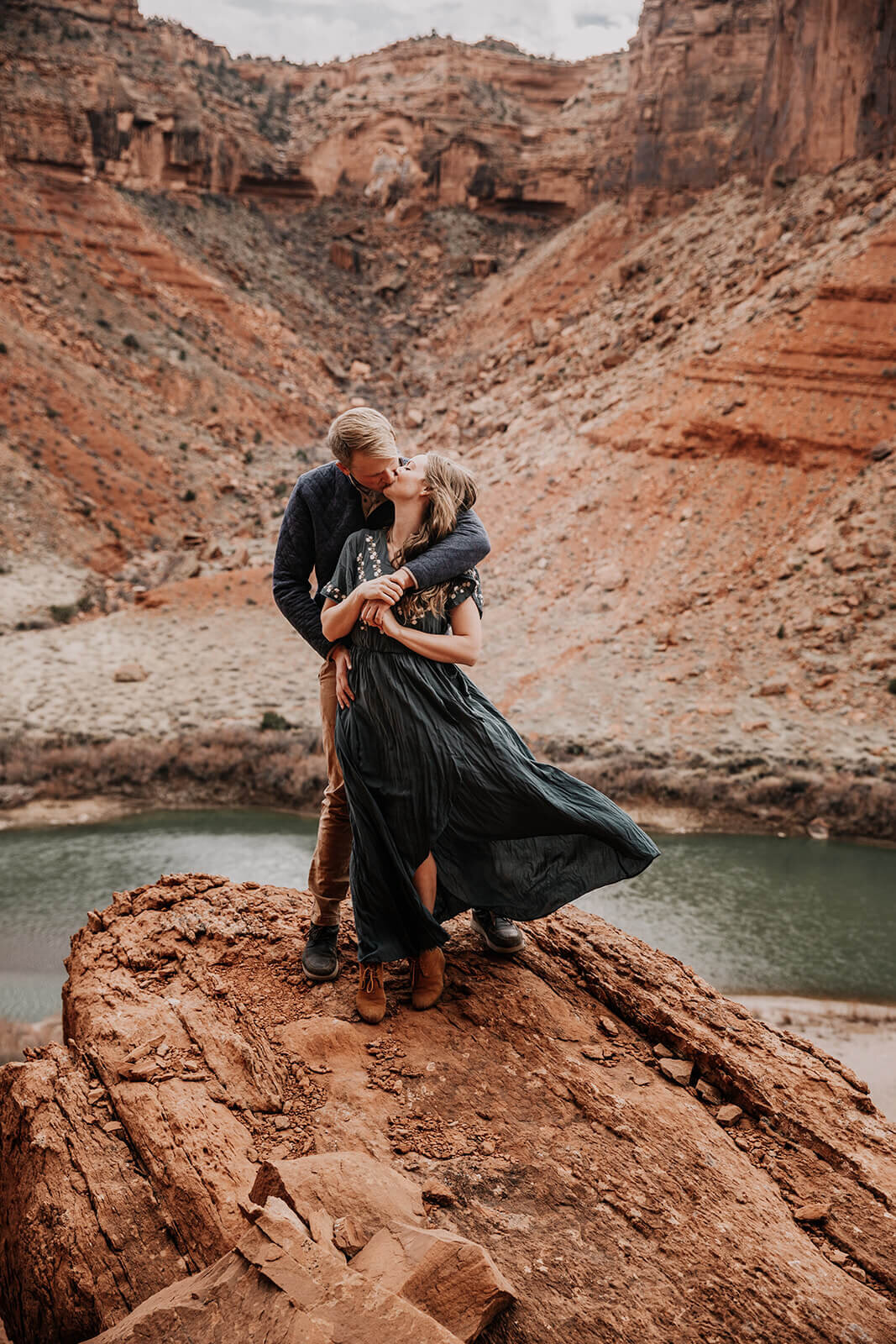  Couple hug on top of red rock feature outside of Moab, Utah during their Utah adventure elopement. Utah elopement photographer. 