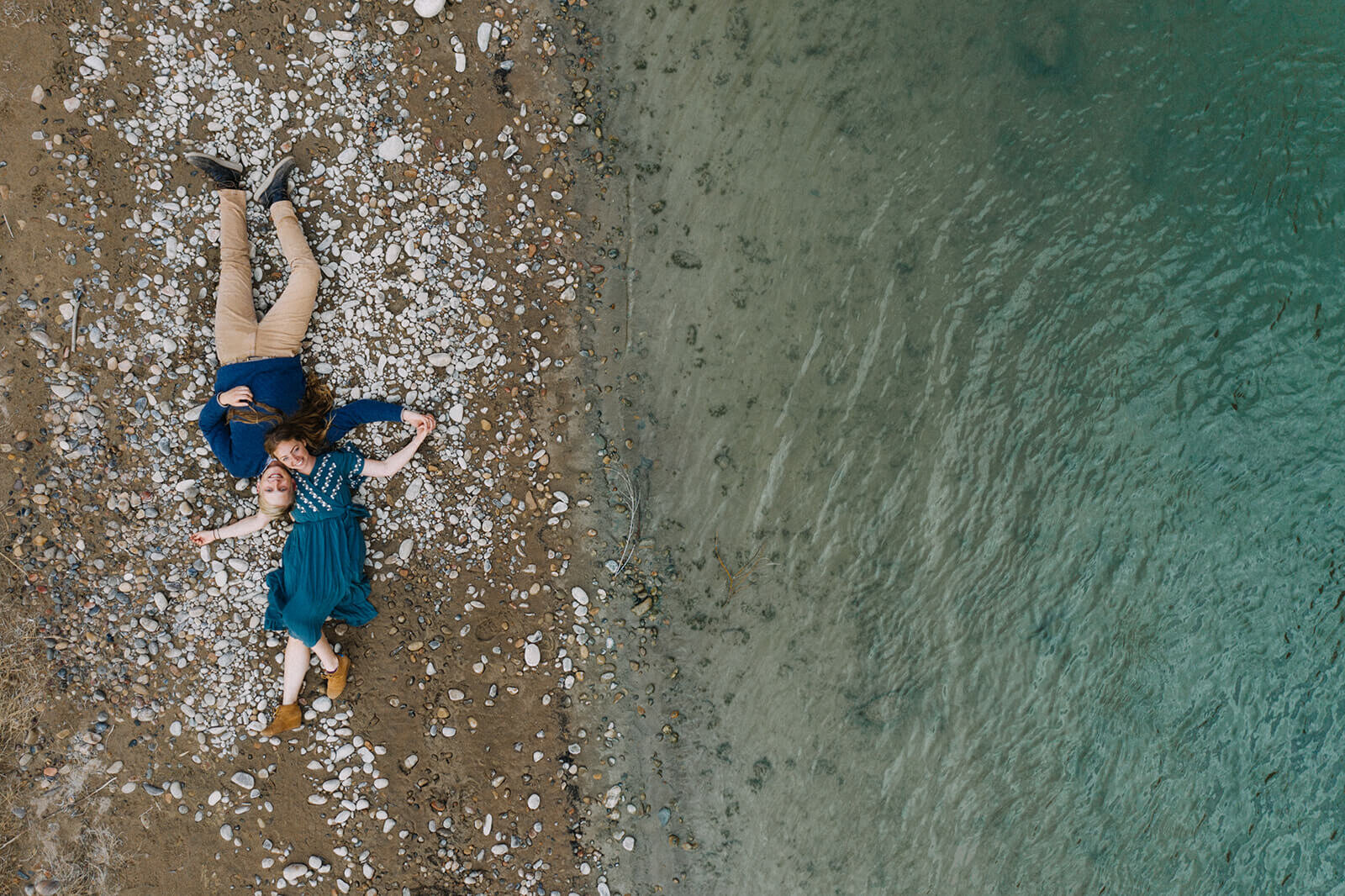  Couple lay on banks of Colorado River outside of Moab, Utah during their Utah adventure elopement. Utah elopement photographer. 