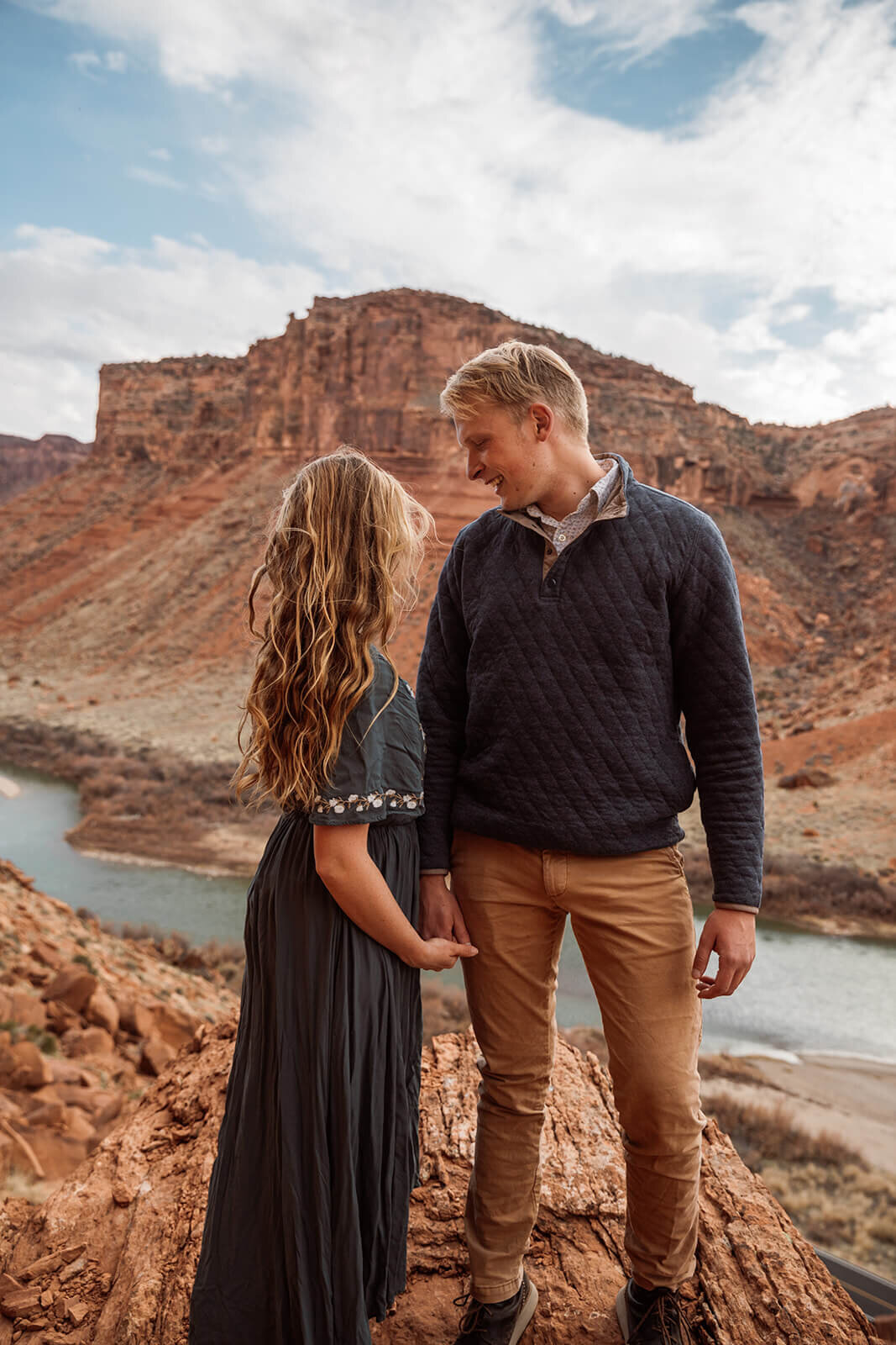  Couple on top of red rock feature overlooking Colorado River outside of Moab, Utah during their Utah adventure elopement. Utah elopement photographer. 