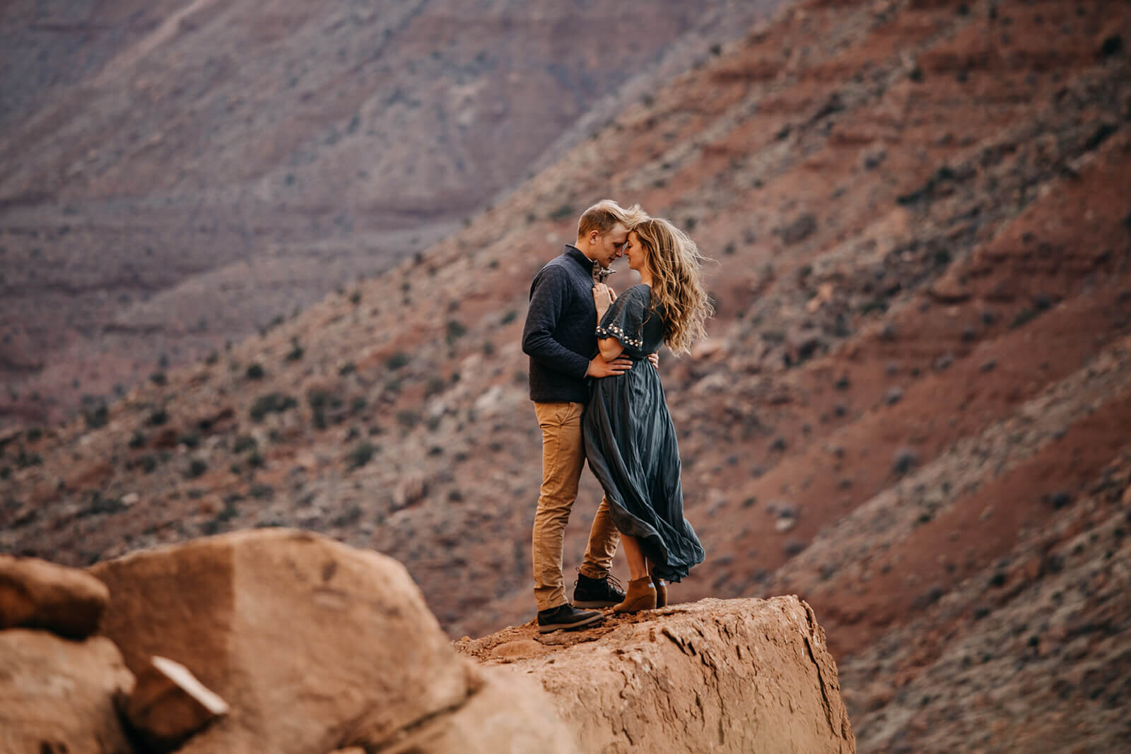 Couple on top of red rock feature stare into each others eyes outside of Moab, Utah during their Utah adventure elopement. Utah elopement photographer. 