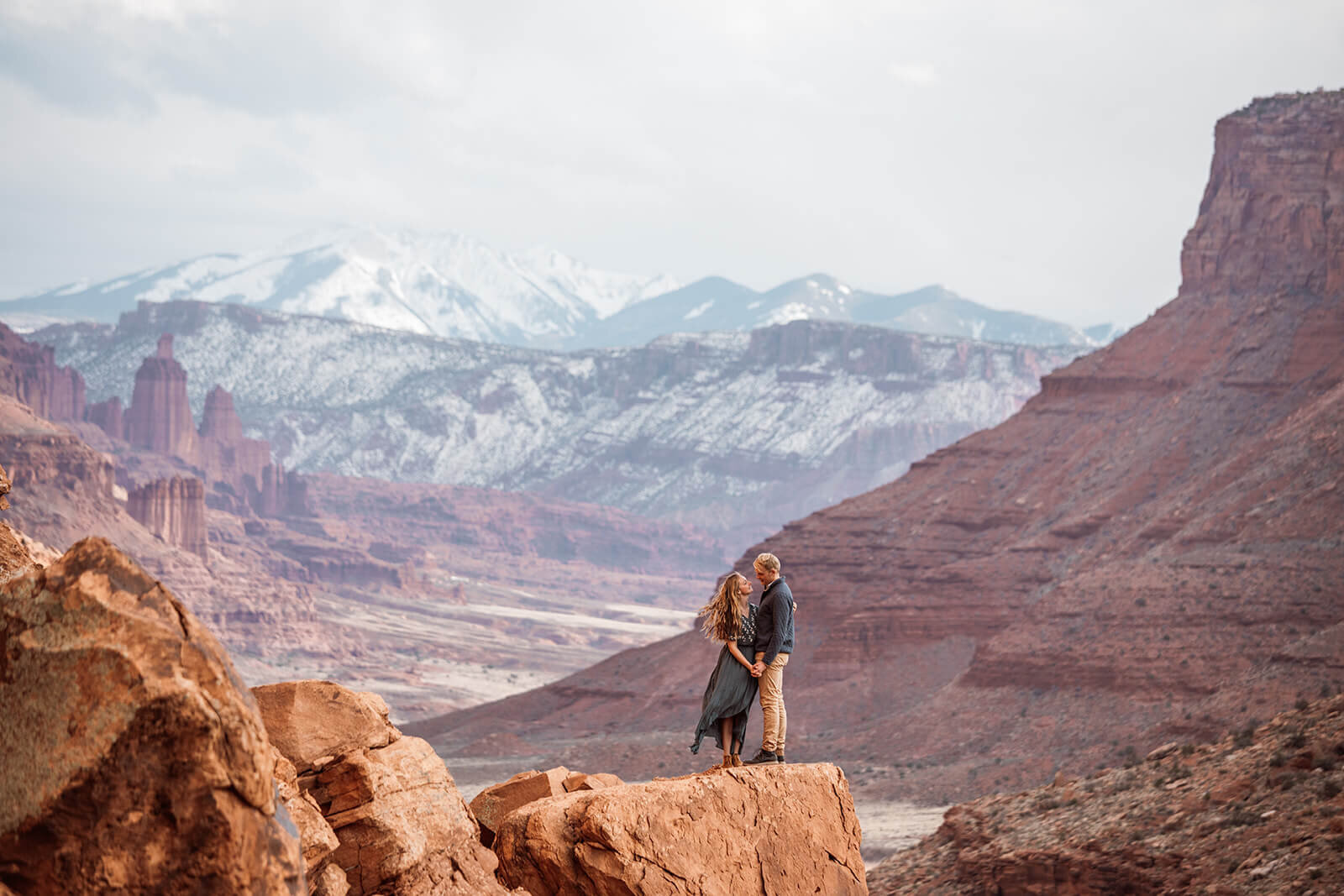  Couple on top of red rock feature in front of the La Sal mountains outside of Moab, Utah during their Utah adventure elopement. Utah elopement photographer. 