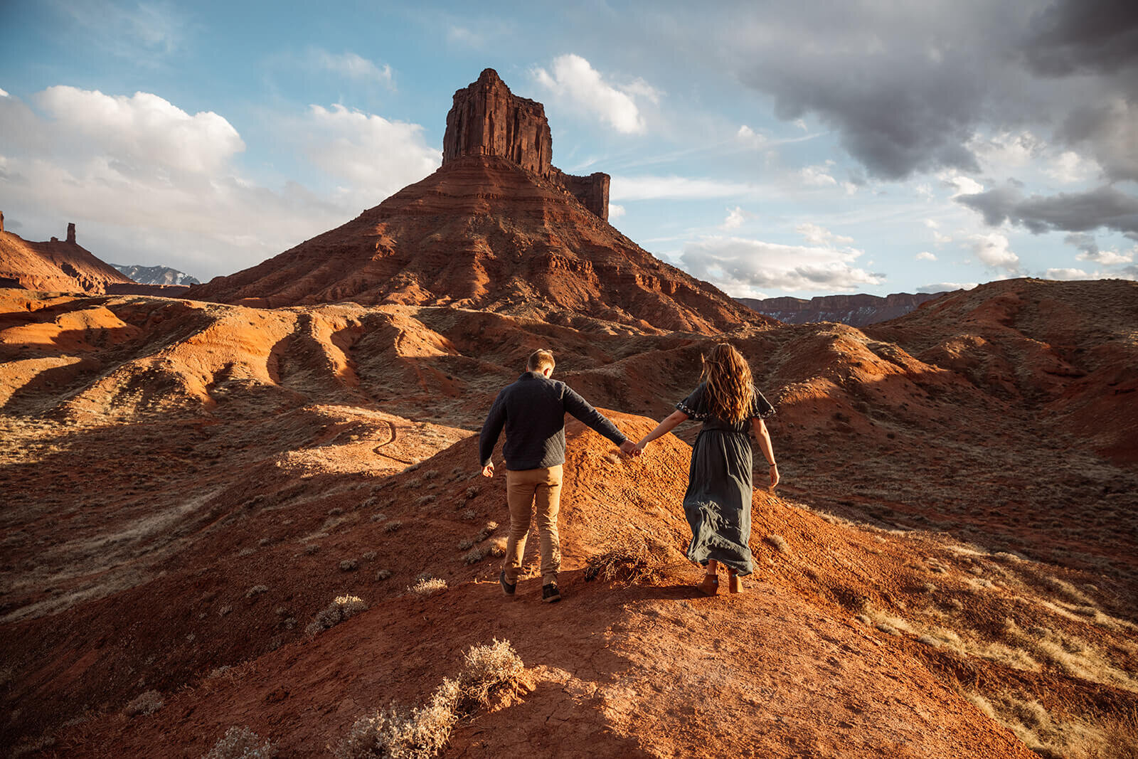  Couple hold hands in front of desert towers on public lands outside of Moab, Utah. Moab elopement photographer. 