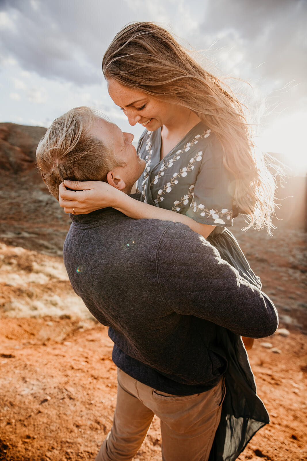  Couple are playful in the setting sun in front of desert towers on public lands outside of Moab, Utah. Moab elopement photographer. 