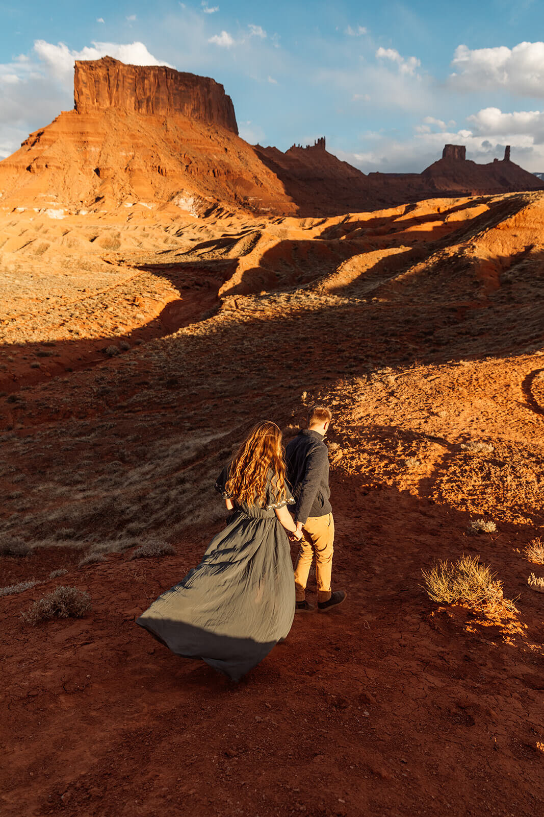  Couple hold hands in front of desert towers on public lands outside of Moab, Utah. Moab elopement photographer. 