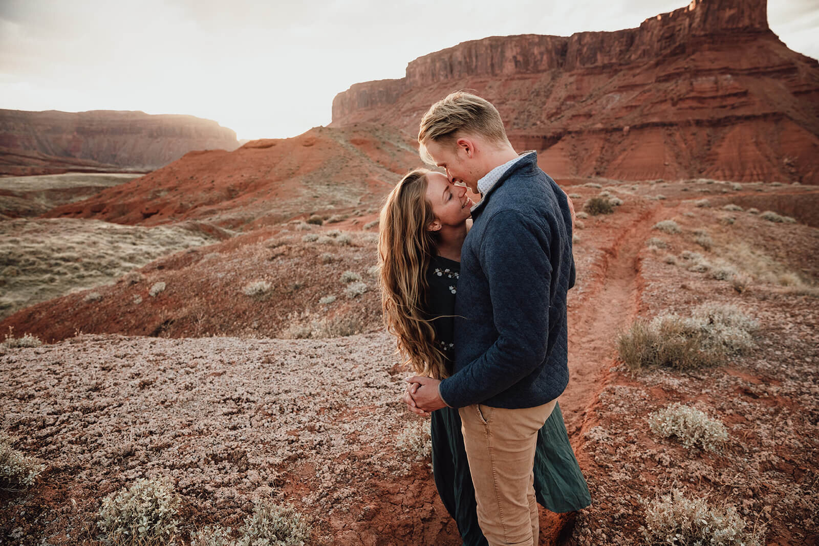  Couple are playful in the setting sun in front of desert towers in the Ida Gulch area outside of Moab, Utah. Moab elopement photographer. 