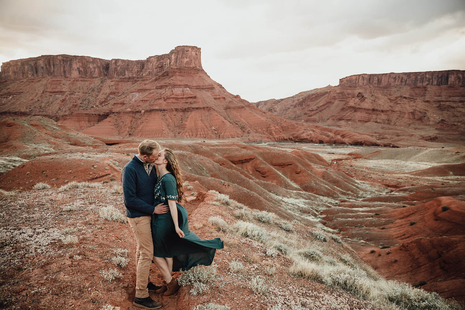  Couple are playful in the setting sun in front of desert towers on public lands outside of Moab, Utah. Moab elopement photographer. 