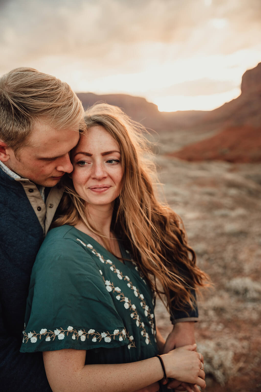  Couple are playful in the setting sun in front of desert towers on public lands outside of Moab, Utah. Moab elopement photographer. 