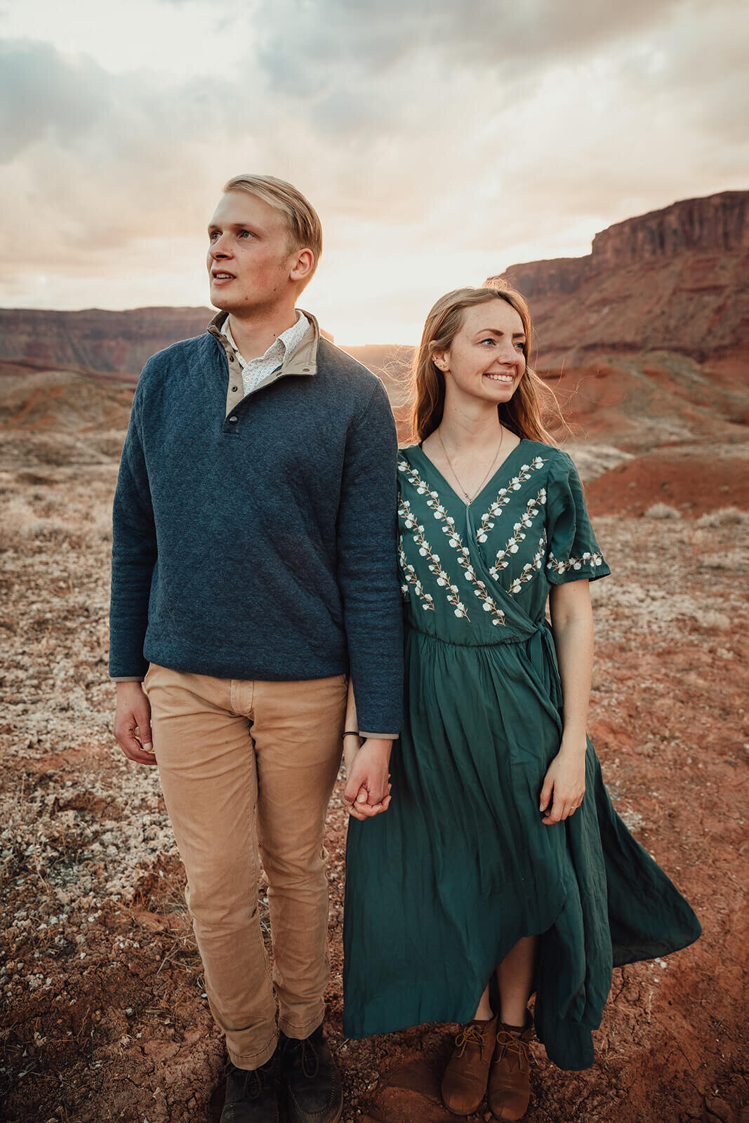  Couple are playful in the setting sun in front of desert towers on public lands outside of Moab, Utah. Desert southwest elopement photographer 