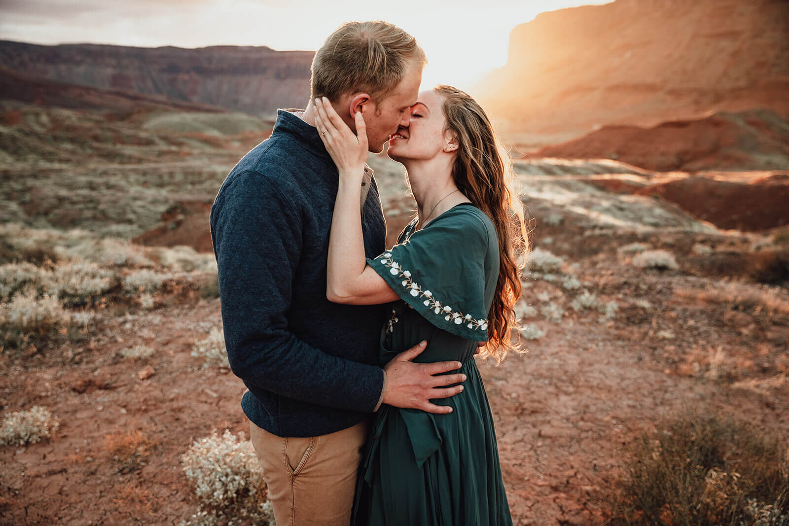  Couple kiss in the setting sun in front of desert towers on public lands outside of Moab, Utah. Desert southwest elopement photographer 