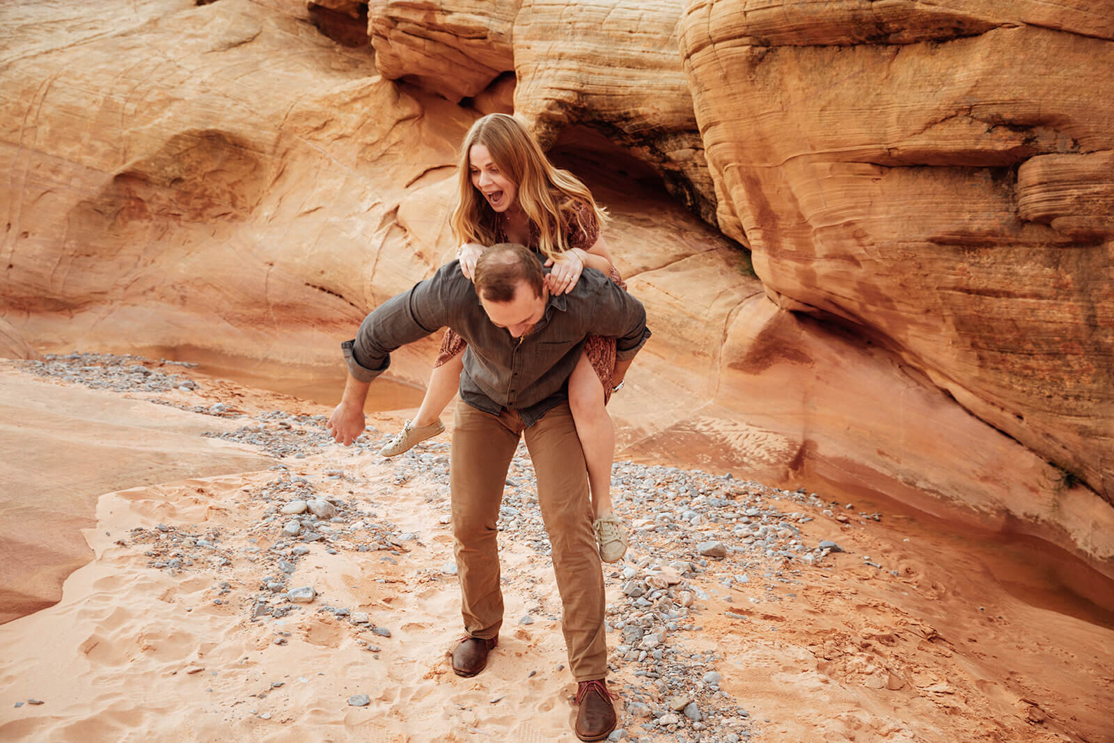  Couple wade through canyon in Valley of Fire State Park next to Lake Mead, outside of Las Vegas, Nevada. Nevada engagement photographer 