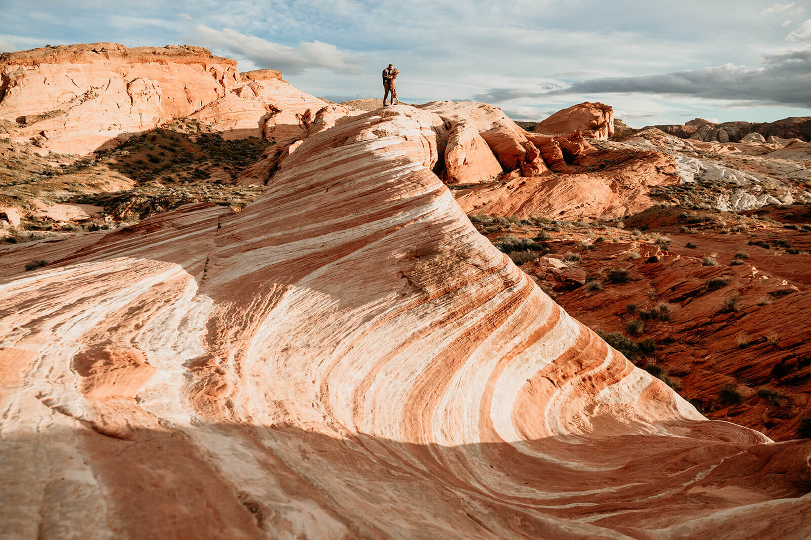  Couple hikes to the Fire Wave in Valley of Fire State Park next to Lake Mead, outside of Las Vegas, Nevada. Las Vegas engagement photographer 