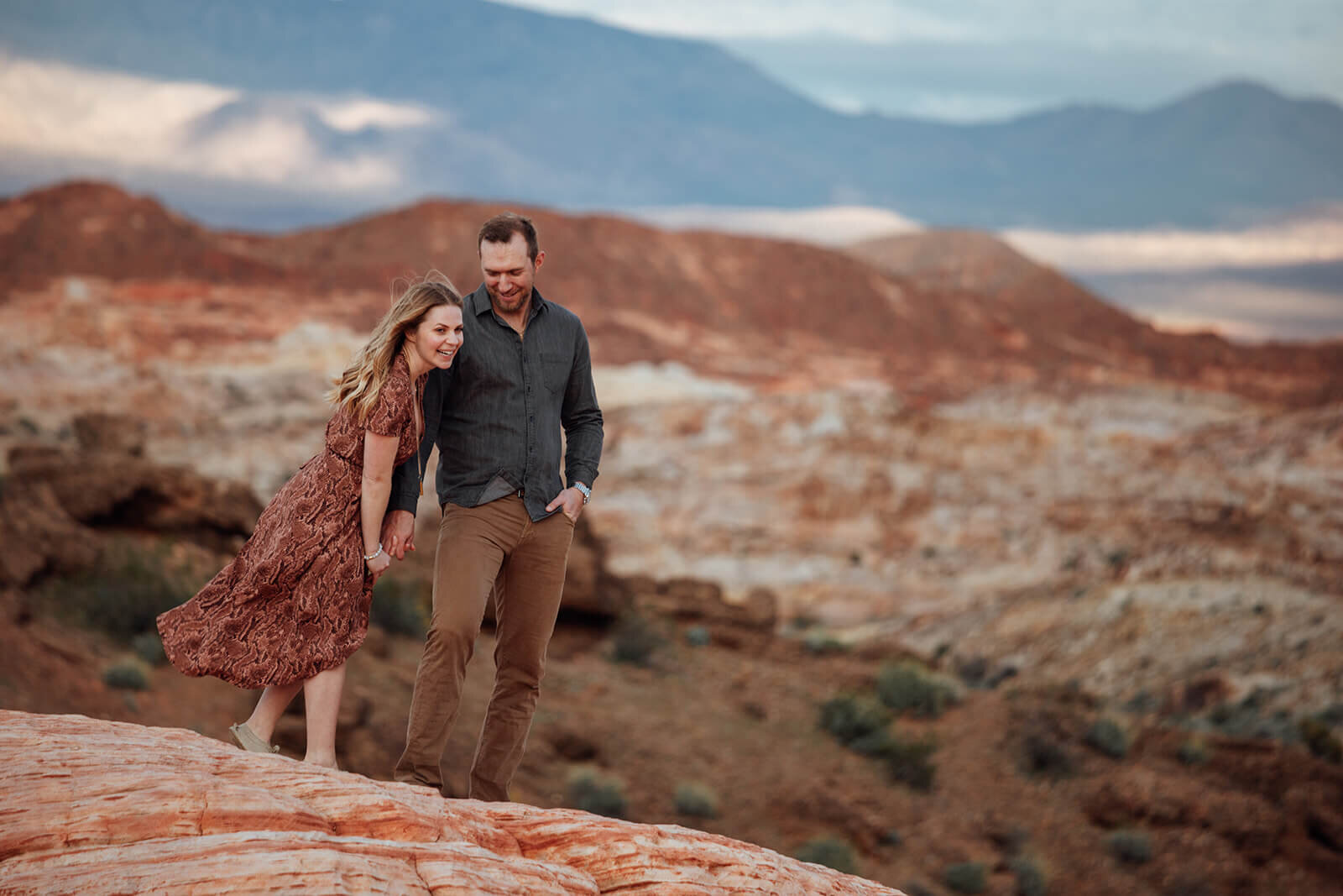  Couple laughs and hikes to the Fire Wave in Valley of Fire State Park next to Lake Mead, outside of Las Vegas, Nevada. Las Vegas engagement photographer 