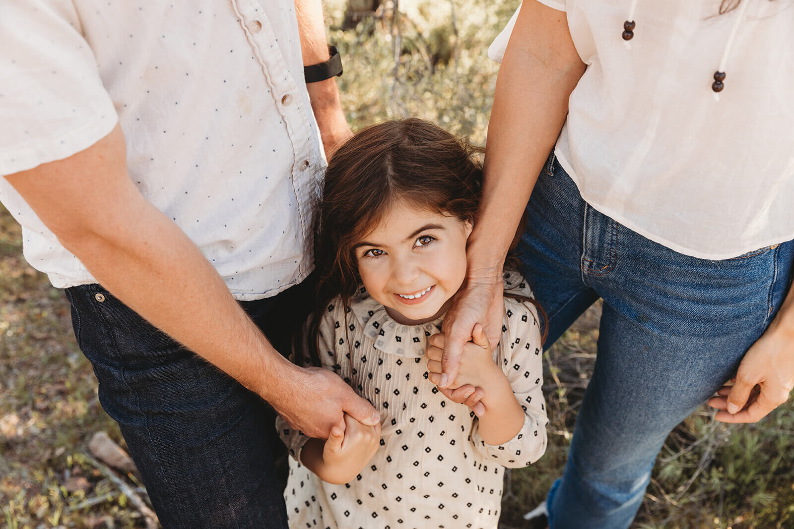  Little girl holds parents hands during their engagement session in the Superstition Mountains outside of Phoenix, Arizona. Arizona elopement photographer 