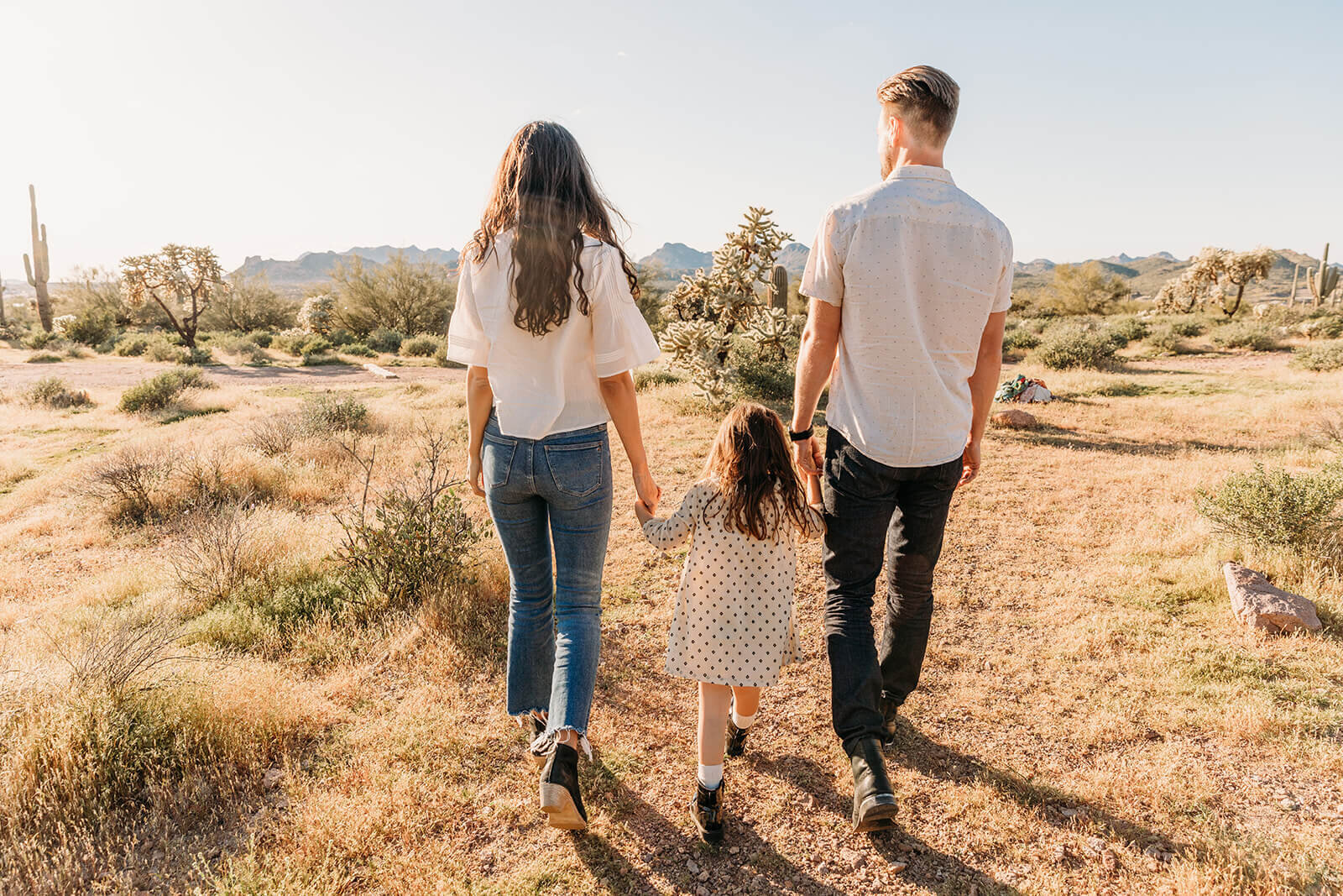  Little girl holds parents hands during their engagement session in the Superstition Mountains outside of Phoenix, Arizona. Arizona elopement photographer 