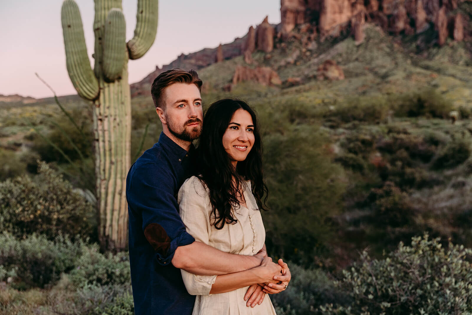  Couple hikes through desert wonderland during sunset during their engagement session in the Superstition Mountains outside of Phoenix, Arizona. Phoenix elopement photographer 