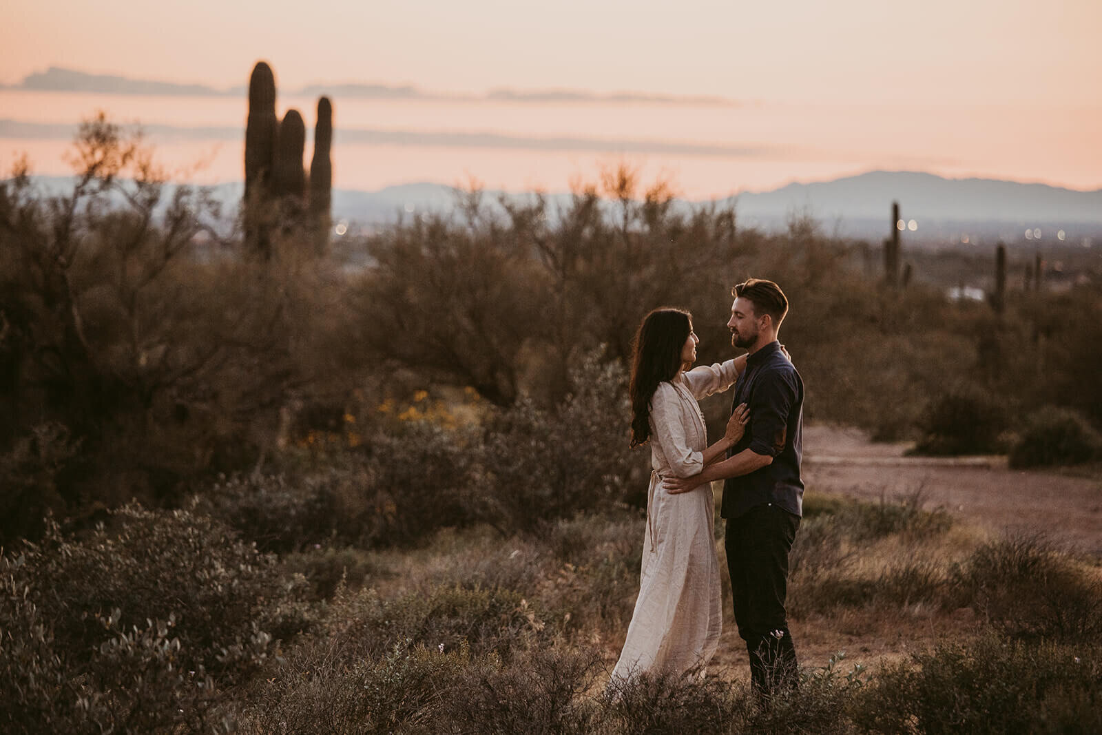  Couple hikes through desert wonderland during sunset during their engagement session in the Superstition Mountains outside of Phoenix, Arizona. Phoenix elopement photographer 