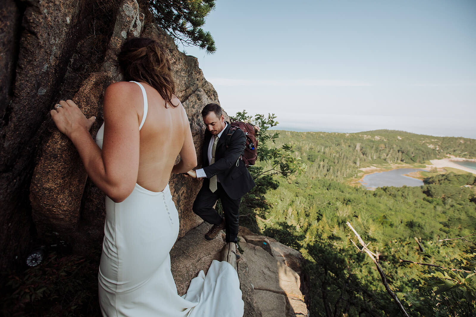  Eloping couple climbs the Beehive in Acadia National Park in Maine in wedding attire. 