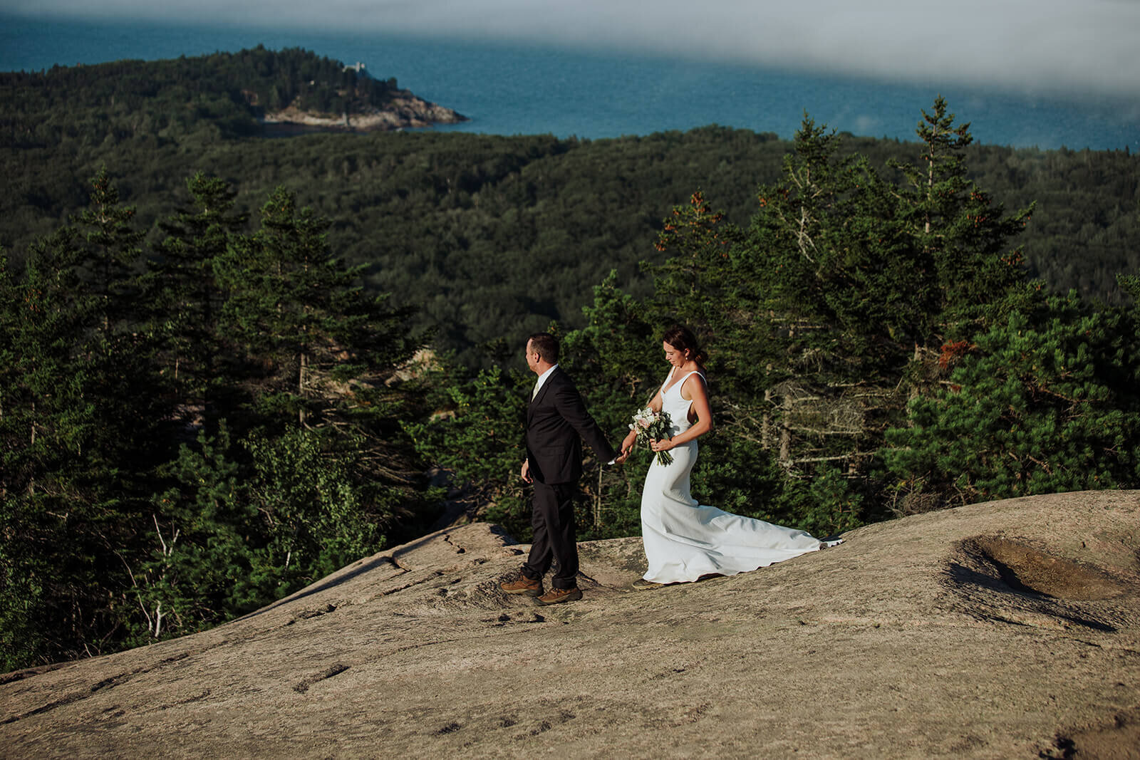  Couple takes in the views at the summit during their Acadia National Park elopement in Maine while hiking the Beehive. 