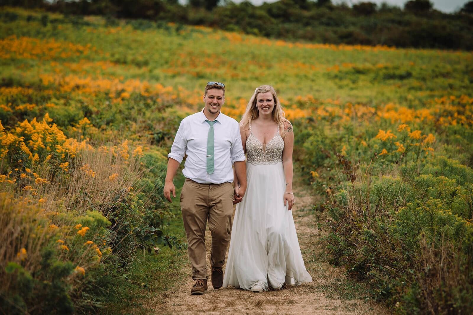  Eloping couple runs through flower fields during their hiking and beach elopement on Block Island off the coast of Rhode Island. 