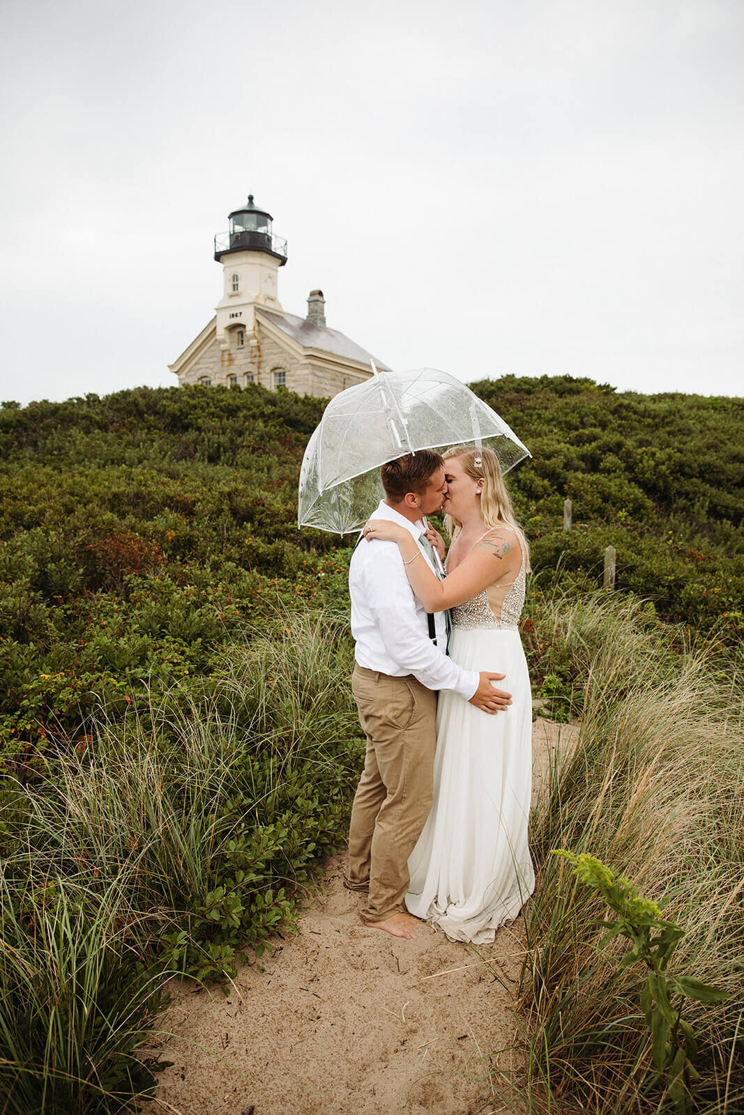  Eloping couple explores a lighthouse in the rain during their hiking and beach elopement on Block Island off the coast of Rhode Island. 