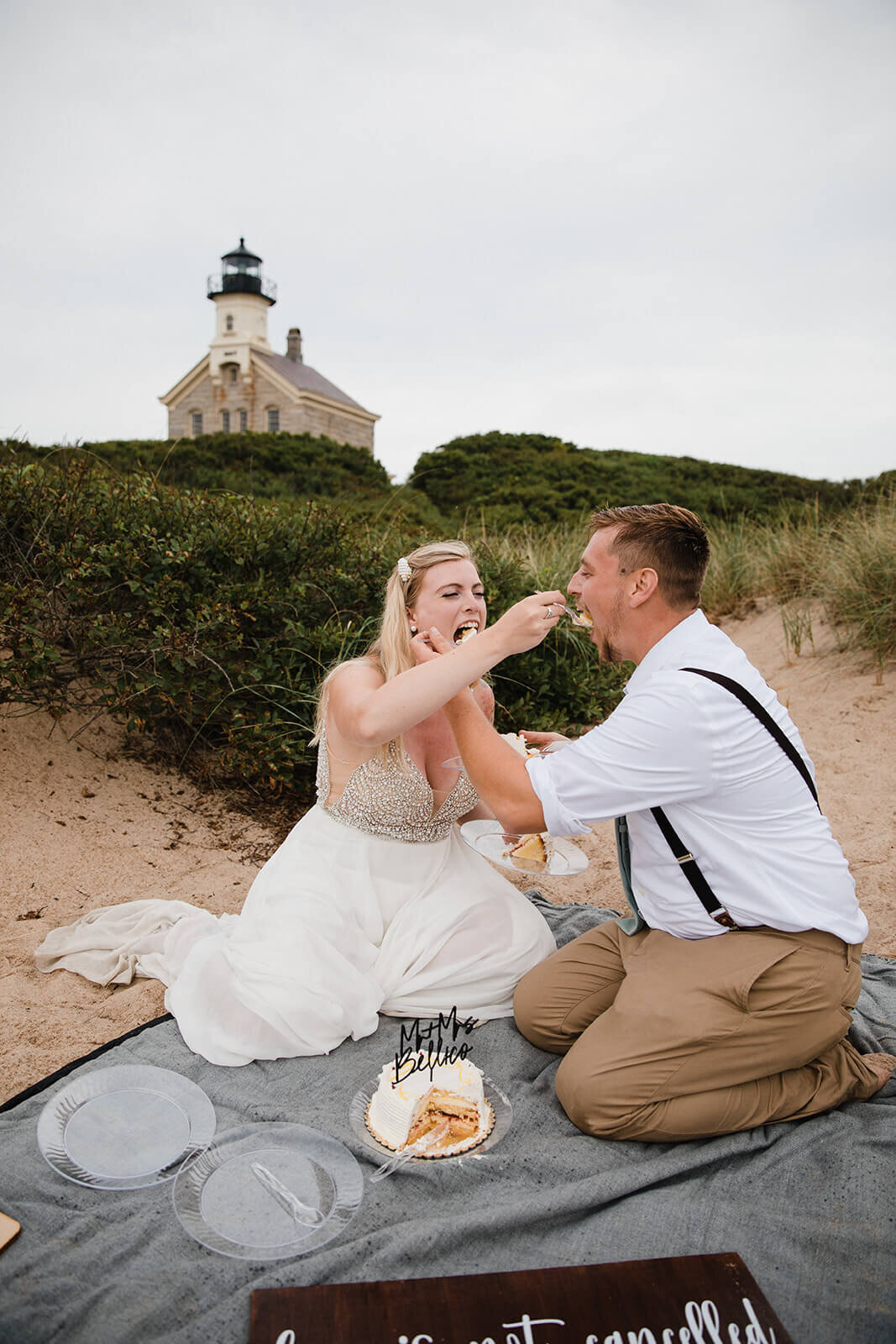  Eloping couple explores a lighthouse and cuts their cake during their hiking and beach elopement on Block Island off the coast of Rhode Island. 