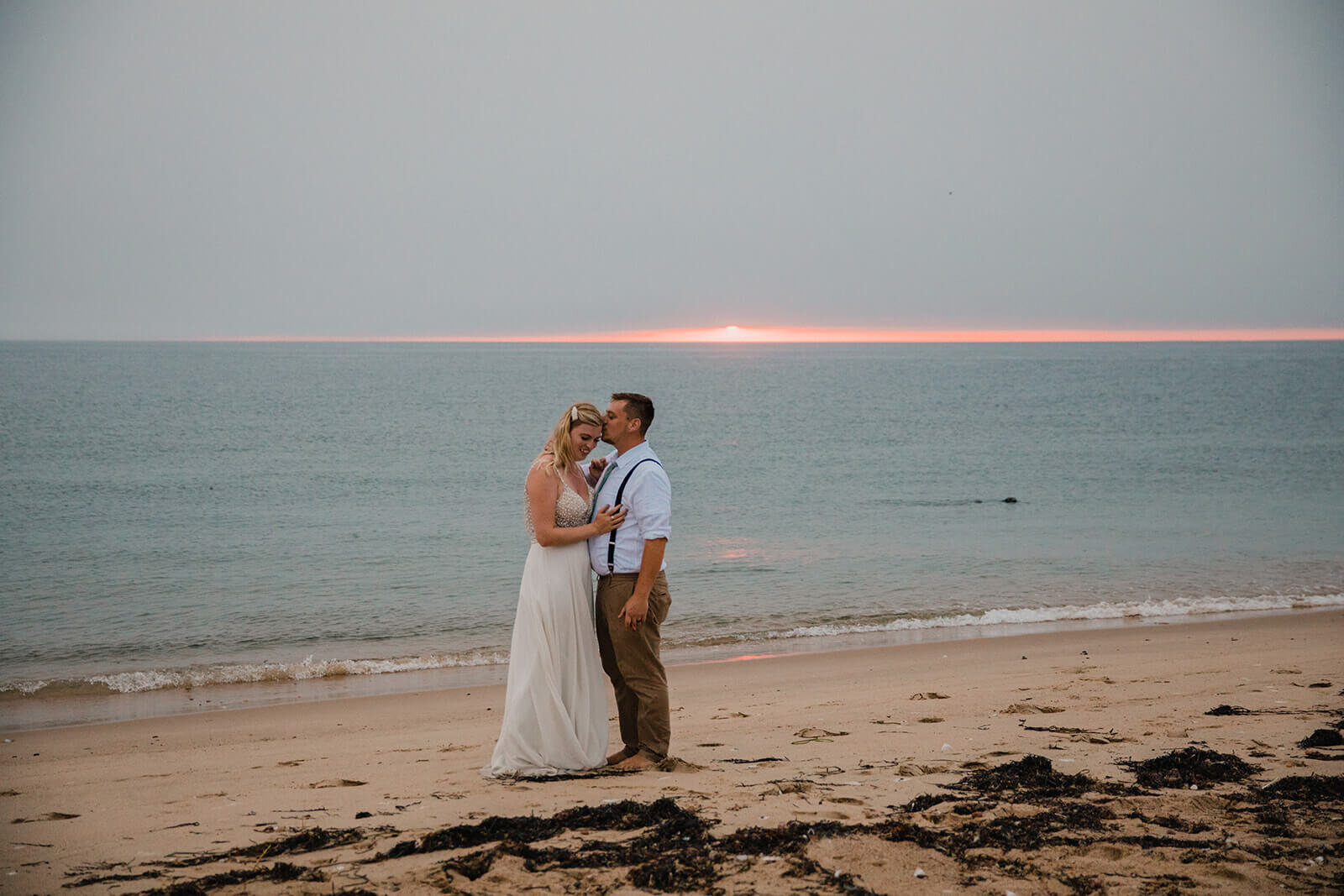  Eloping couple explores coastal views and sees a seal pop up during sunset as part of their hiking and beach elopement on Block Island off the coast of Rhode Island. 