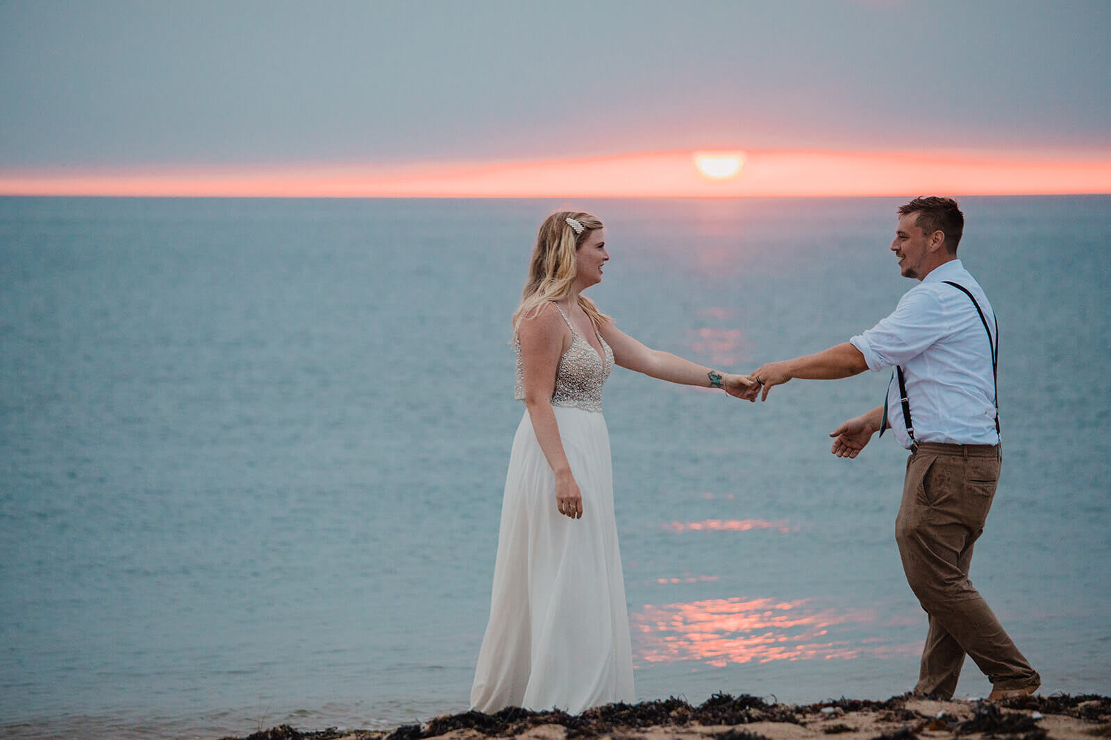  Eloping couple explores coastal views and sees a seal pop up during sunset as part of their hiking and beach elopement on Block Island off the coast of Rhode Island. 