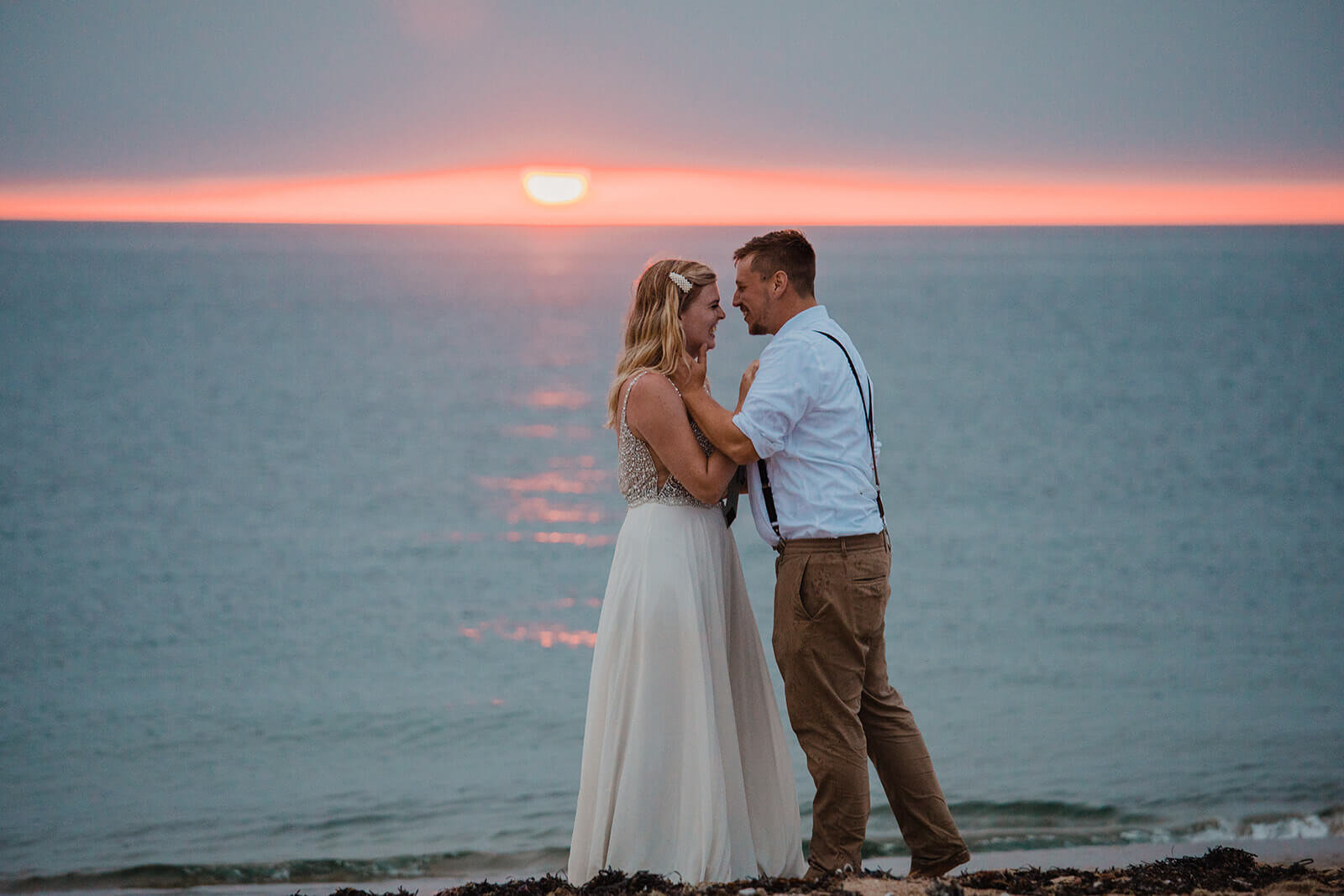  Eloping couple explores coastal views and sees a seal pop up during sunset as part of their hiking and beach elopement on Block Island off the coast of Rhode Island. 