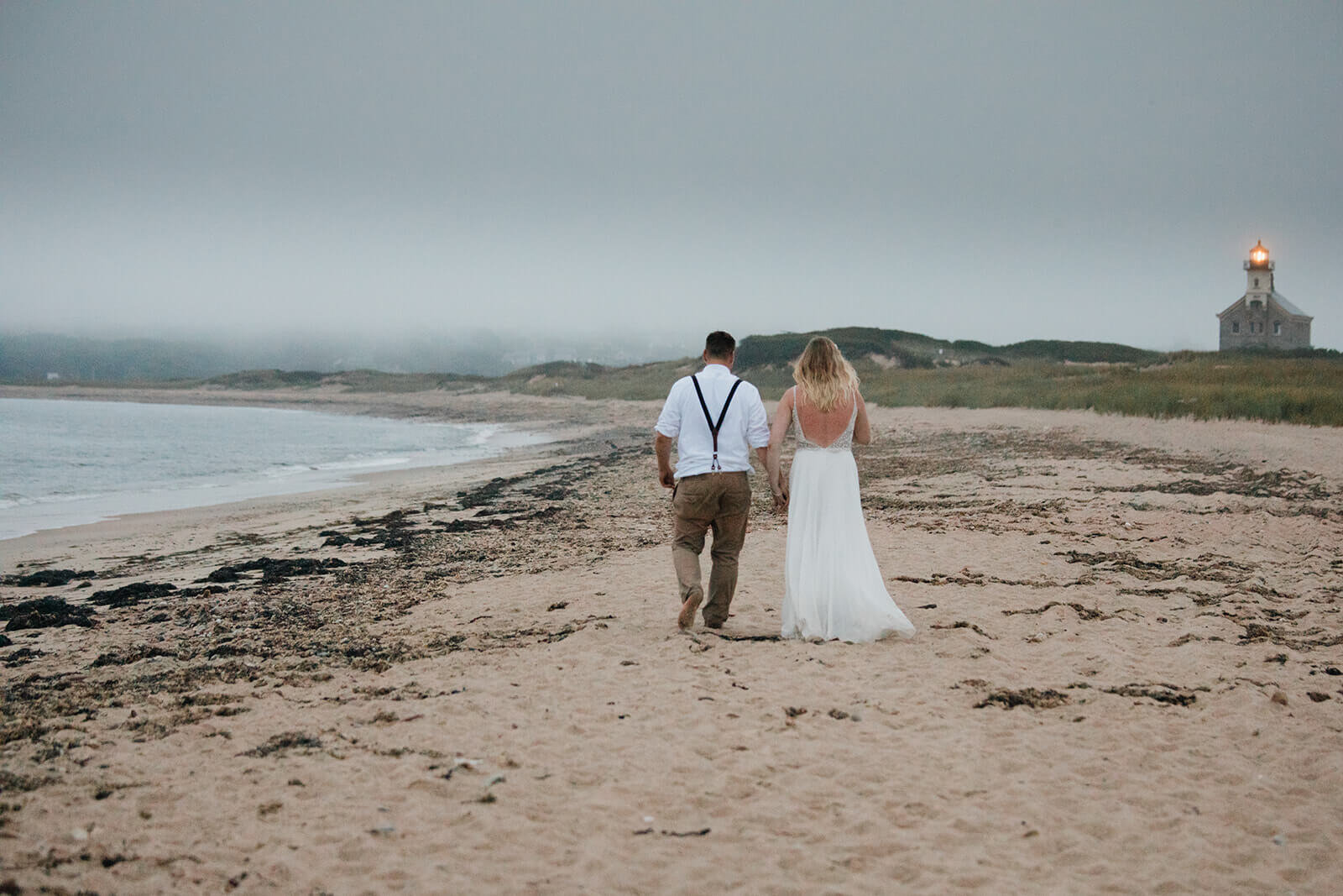  Eloping couple explores coastal views and sees a seal pop up during sunset as part of their hiking and beach elopement on Block Island off the coast of Rhode Island. 