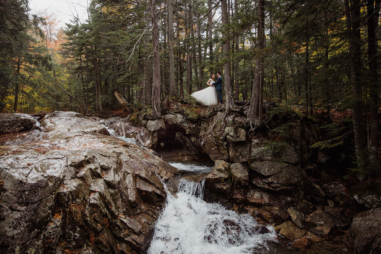  Couple explores the forest in the rain in Franconia Notch State Park in New Hampshire after their elopement ceremony. New Hampshire elopement packages. 
