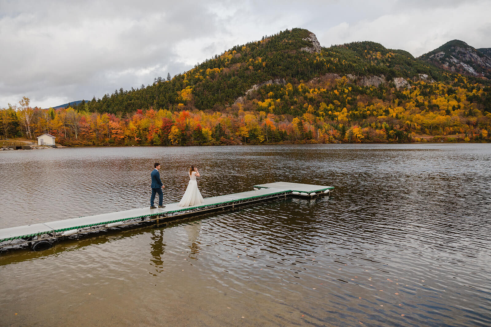  Couple explores the beach in the rainy misty weather in Franconia Notch State Park in New Hampshire after their elopement ceremony. New Hampshire elopement packages. 