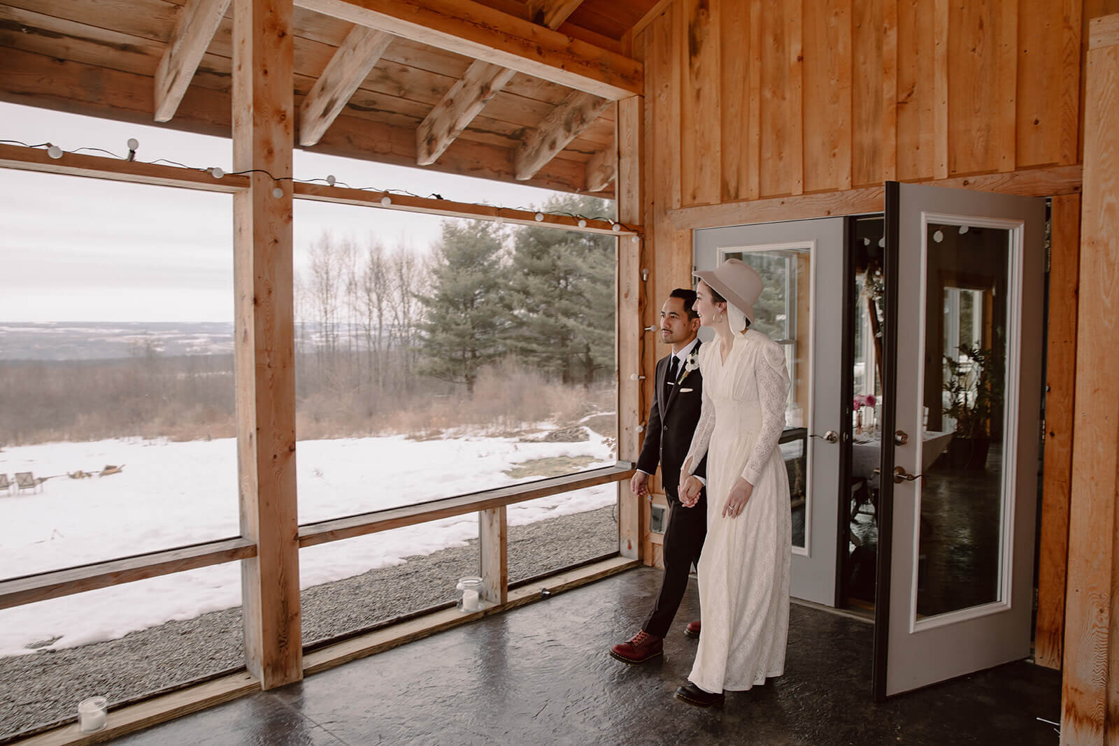  Stylish NYC couple elope late winter in the Finger Lakes region of Upstate NY. Couple walks out of the cabin 