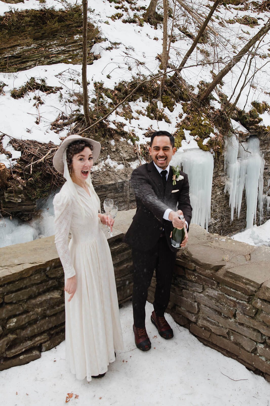  Stylish NYC couple elope late winter in the Finger Lakes region of Upstate NY. Couple pops champagne in celebration. 