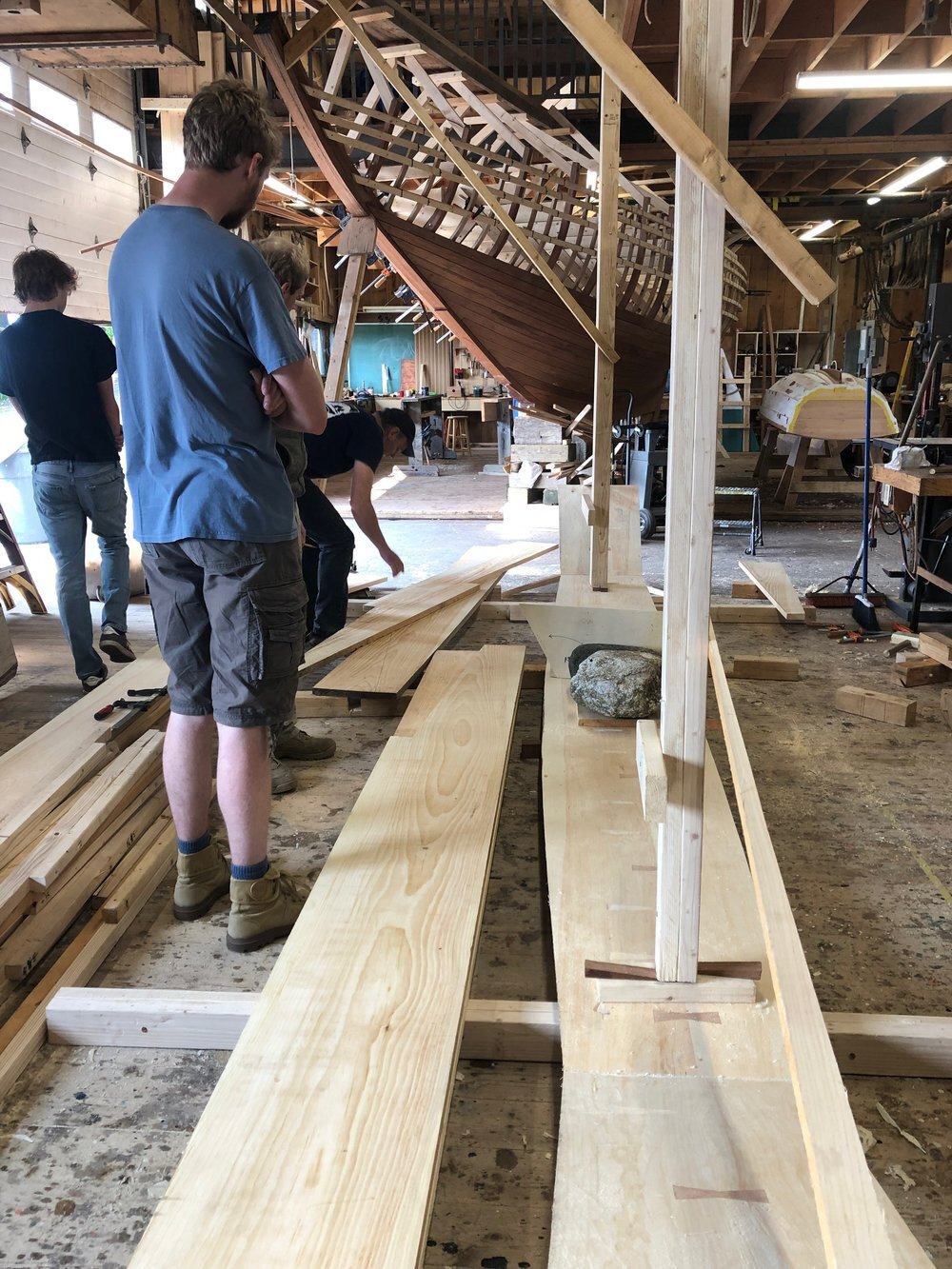  Once the bottom planks are nailed together, they are propped in place and weighted down with rocks. Work can begin on the side planks now. 