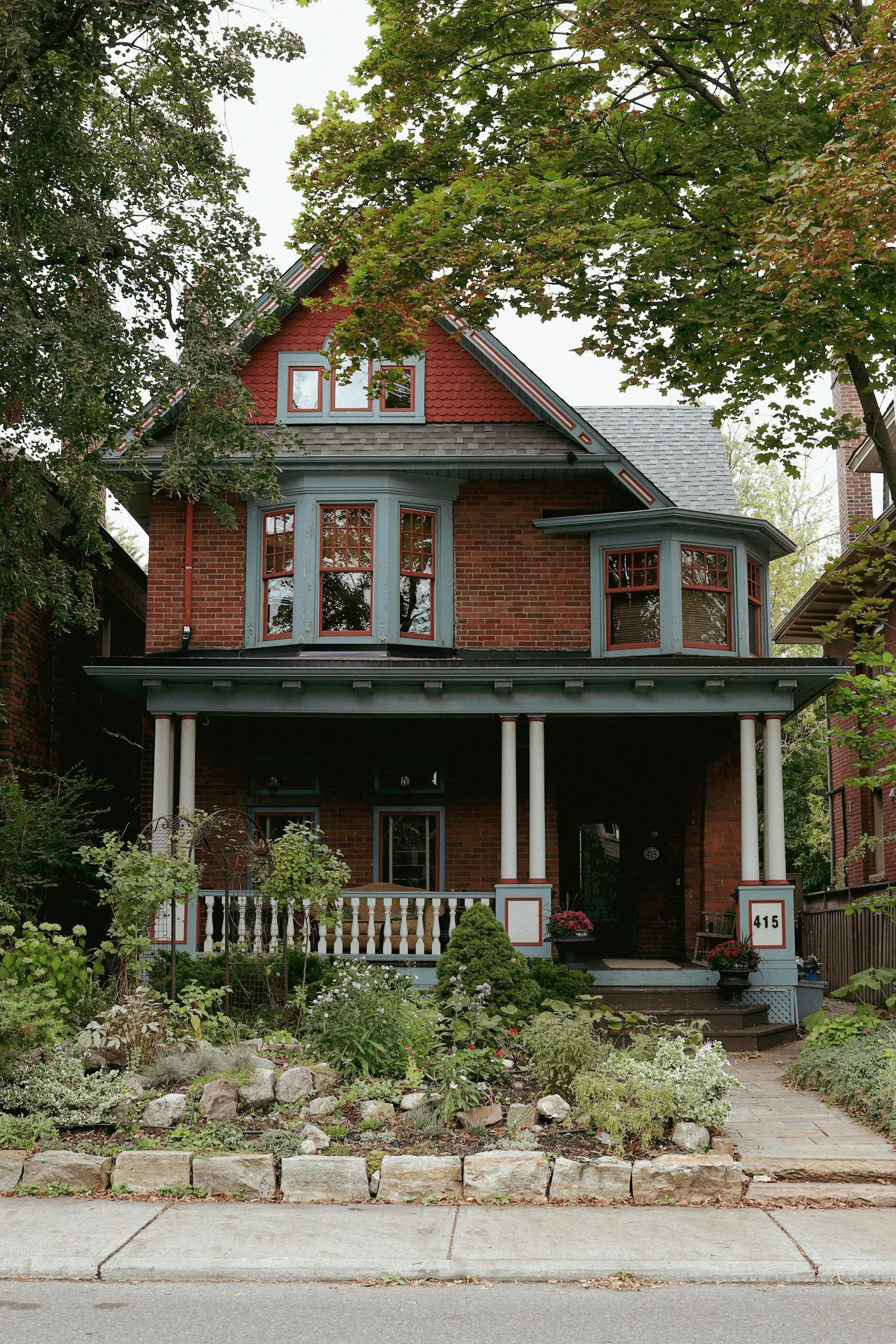 Red brick Toronto house with a covered front porch and garden
