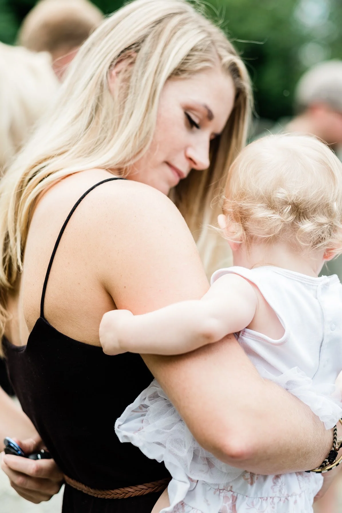 The baby is held by one of her godparents as the ceremony is taking place.
