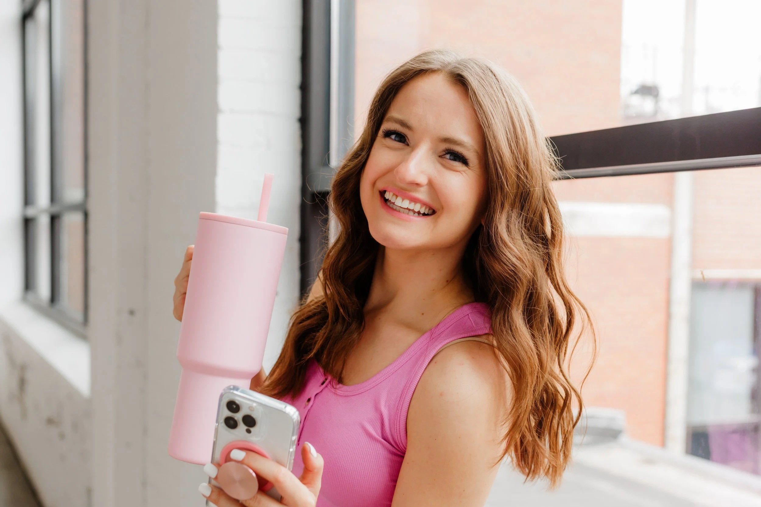 Brand photo of woman holding phone and pink water cup